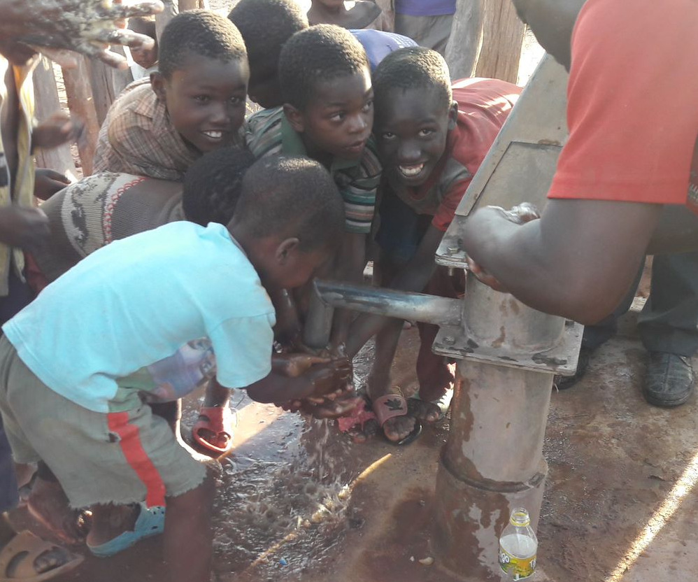 Muuka village children eagerly reach for clean water now flowing from a fixed water pump.