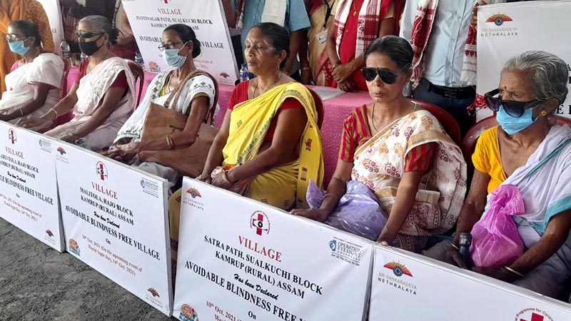 A group of senior woman, wearing eyeglasses and holing banners that read avoidable blindness-free village