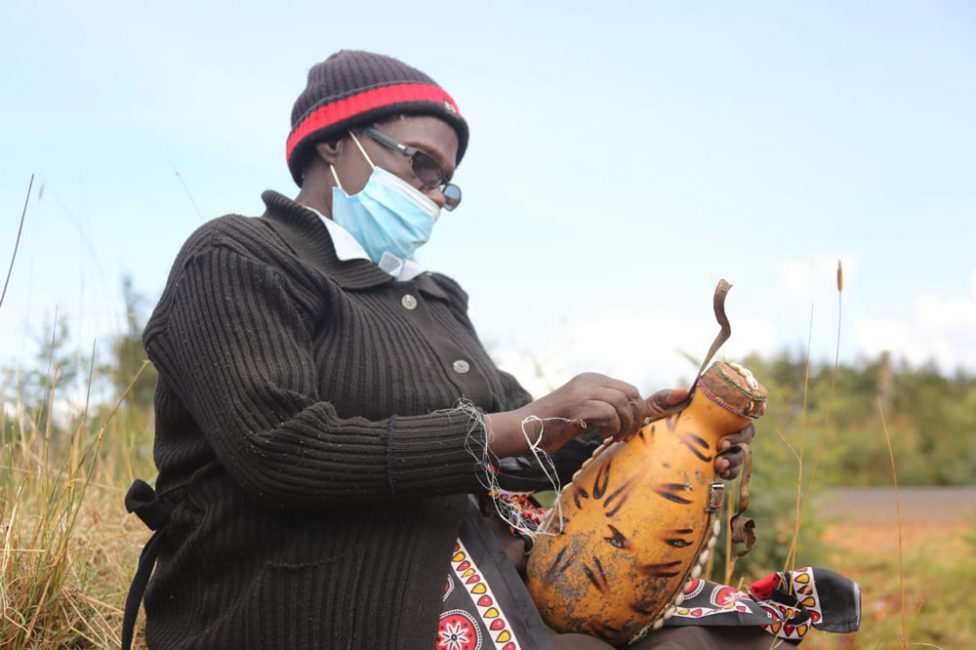 A senior woman, wearing eyeglasses, works on her Sotet, a traditional guard that's used to turn fresh milk into sour milk.