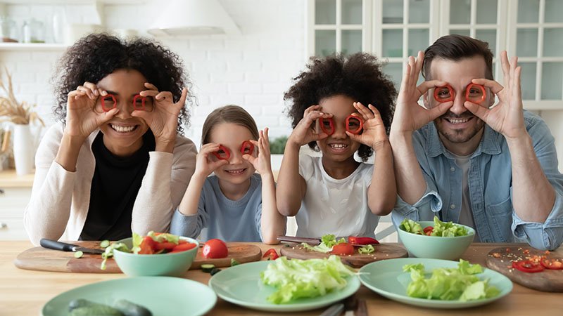 A family of four poses for the camera, holding red pepper rings up over their eyes.
