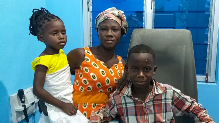 A woman poses with a little girl and a teenaged boy. The children are recovering from surgery for cataracts.
