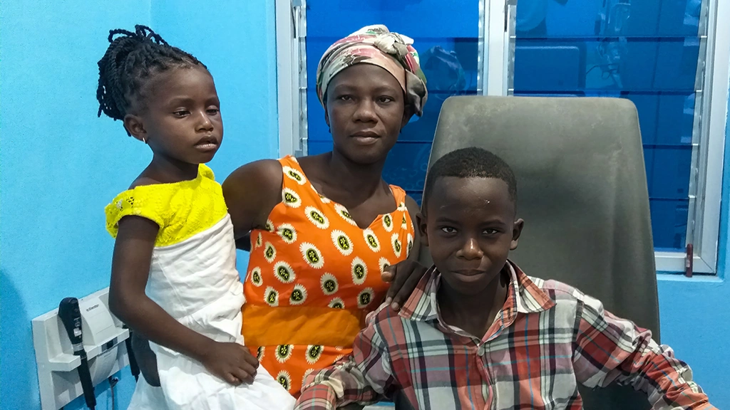 A woman poses with a little girl and a teenaged boy. The children are recovering from surgery for cataracts.