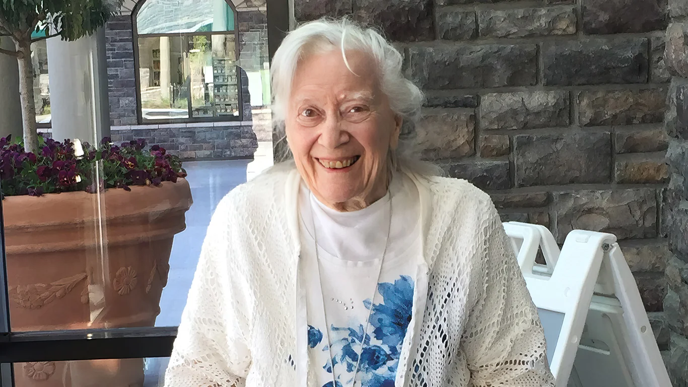 A woman with white hair smiles at the camera.