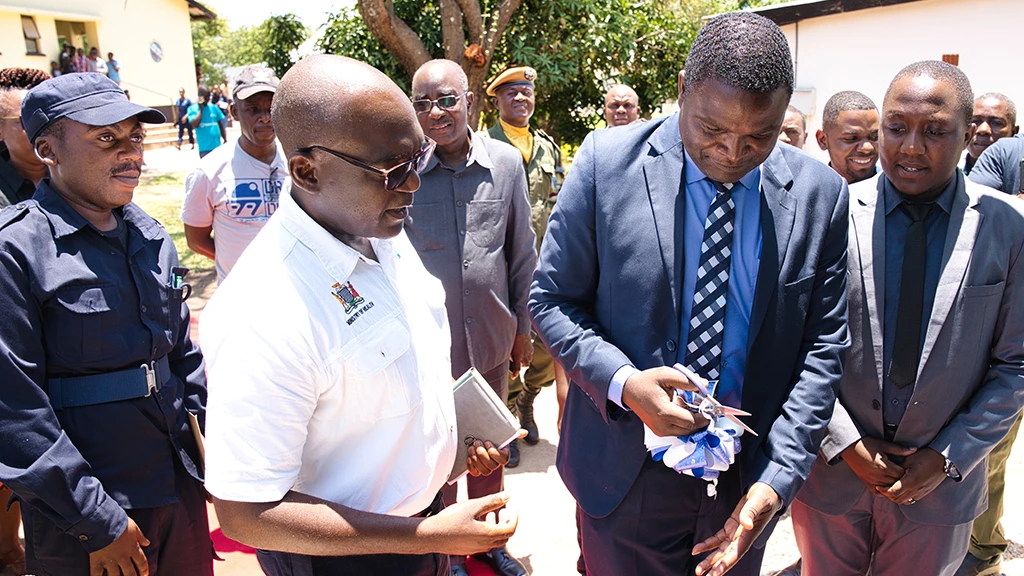 A group of men cut a ribbon at a ceremony.
