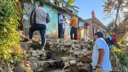 Men climb steep stairs towards a group of houses clustered on a hill.