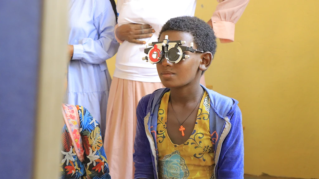 A girl wears a pair of refracting frames while getting an eye exam.